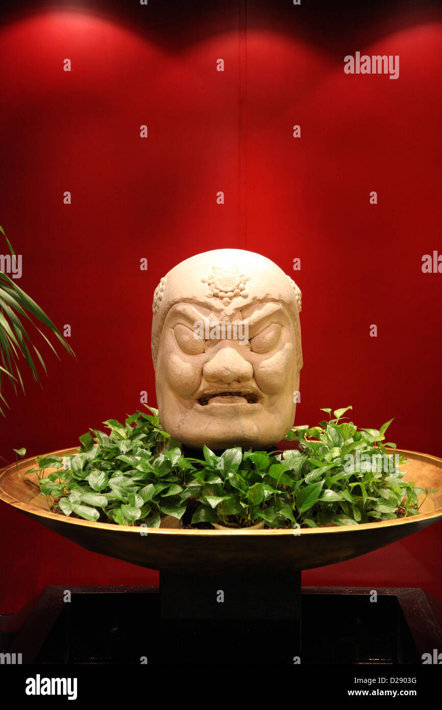 It's a photo of a statue on a red background. It is a Buddha head or bas-relief of a dragon Stock Photo