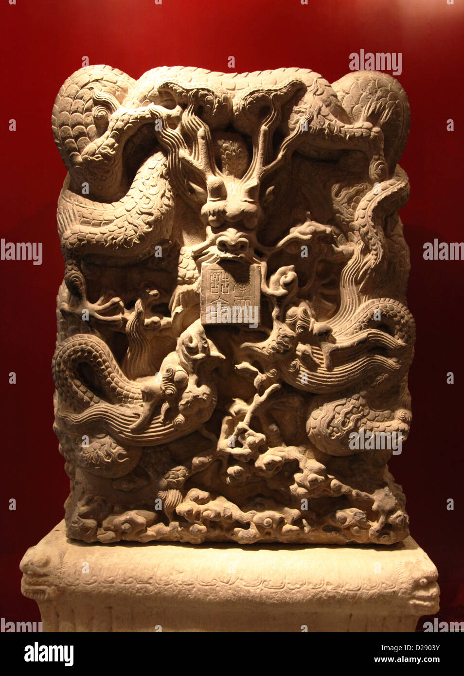 It's a photo of a statue on a red background. It is a Buddha head or bas-relief of a dragon Stock Photo