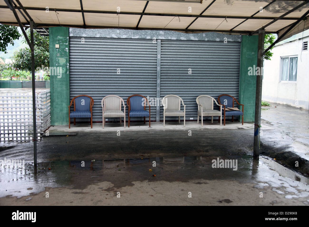 It's a photo of 6 chairs or seats that stand side by side in front of a closed shop in Hong Kong Stock Photo