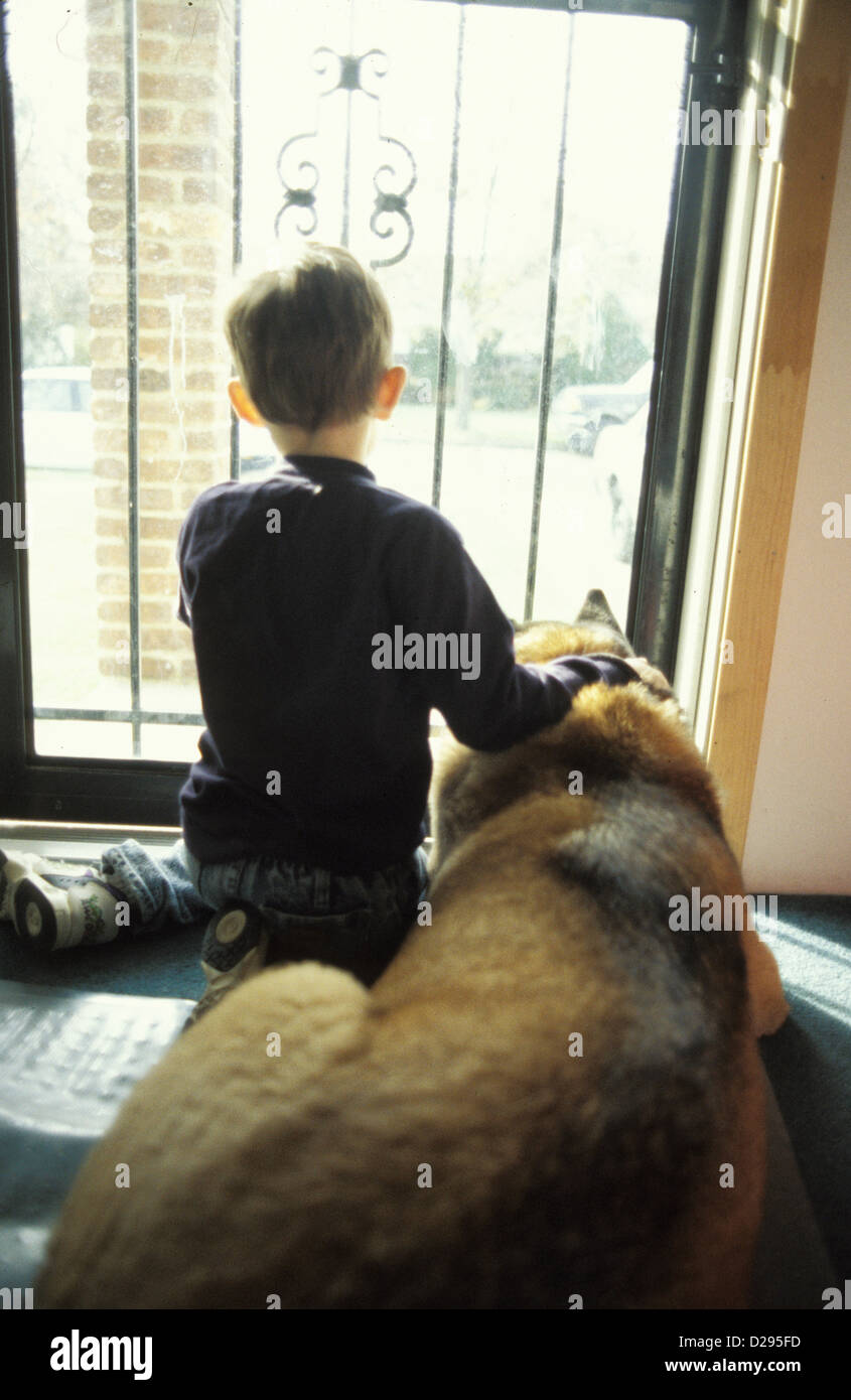 5 1/2 Year Old Boy With Dog. Looking Out Door Stock Photo