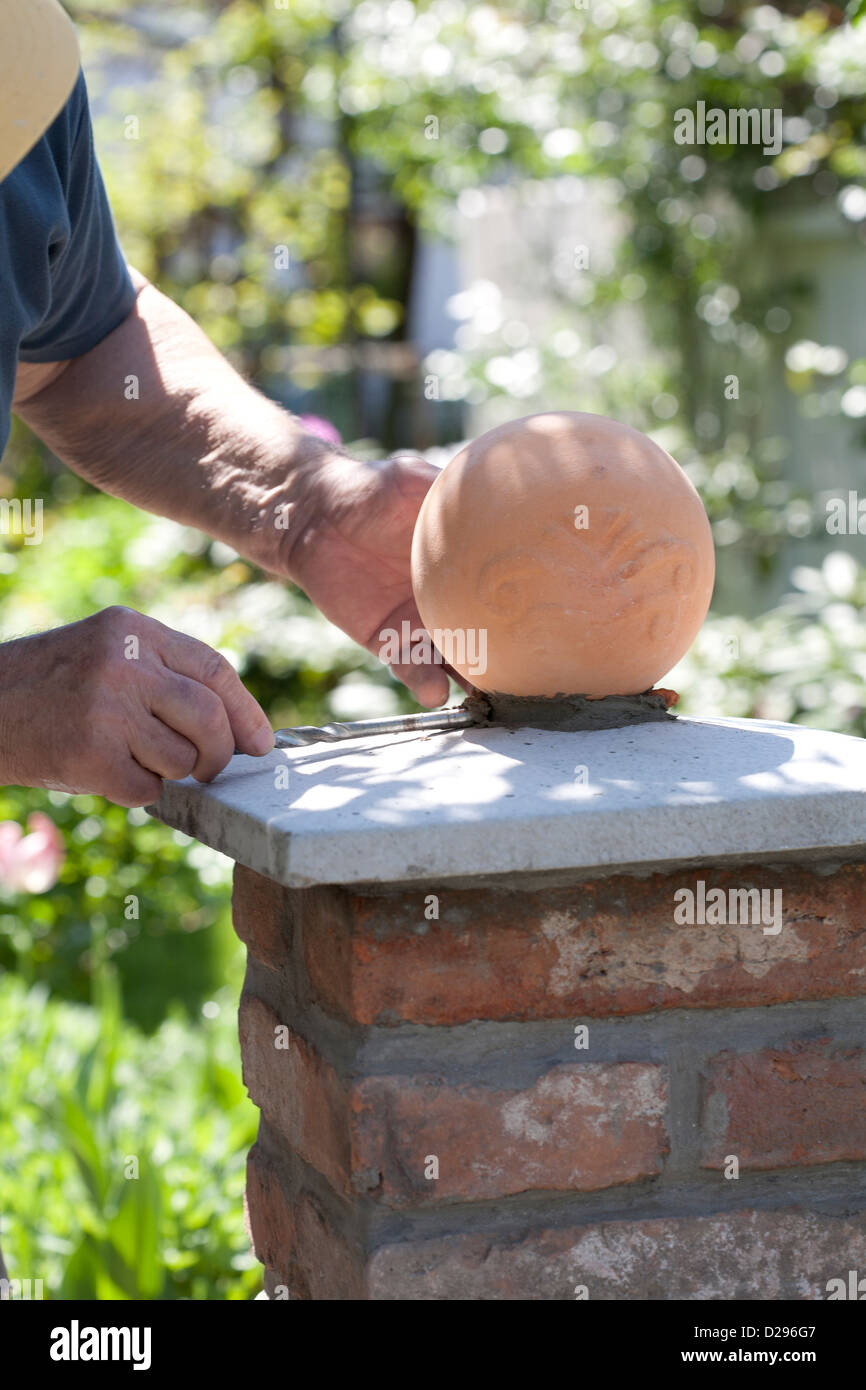 Building a brick pillar with ball finial. Stock Photo
