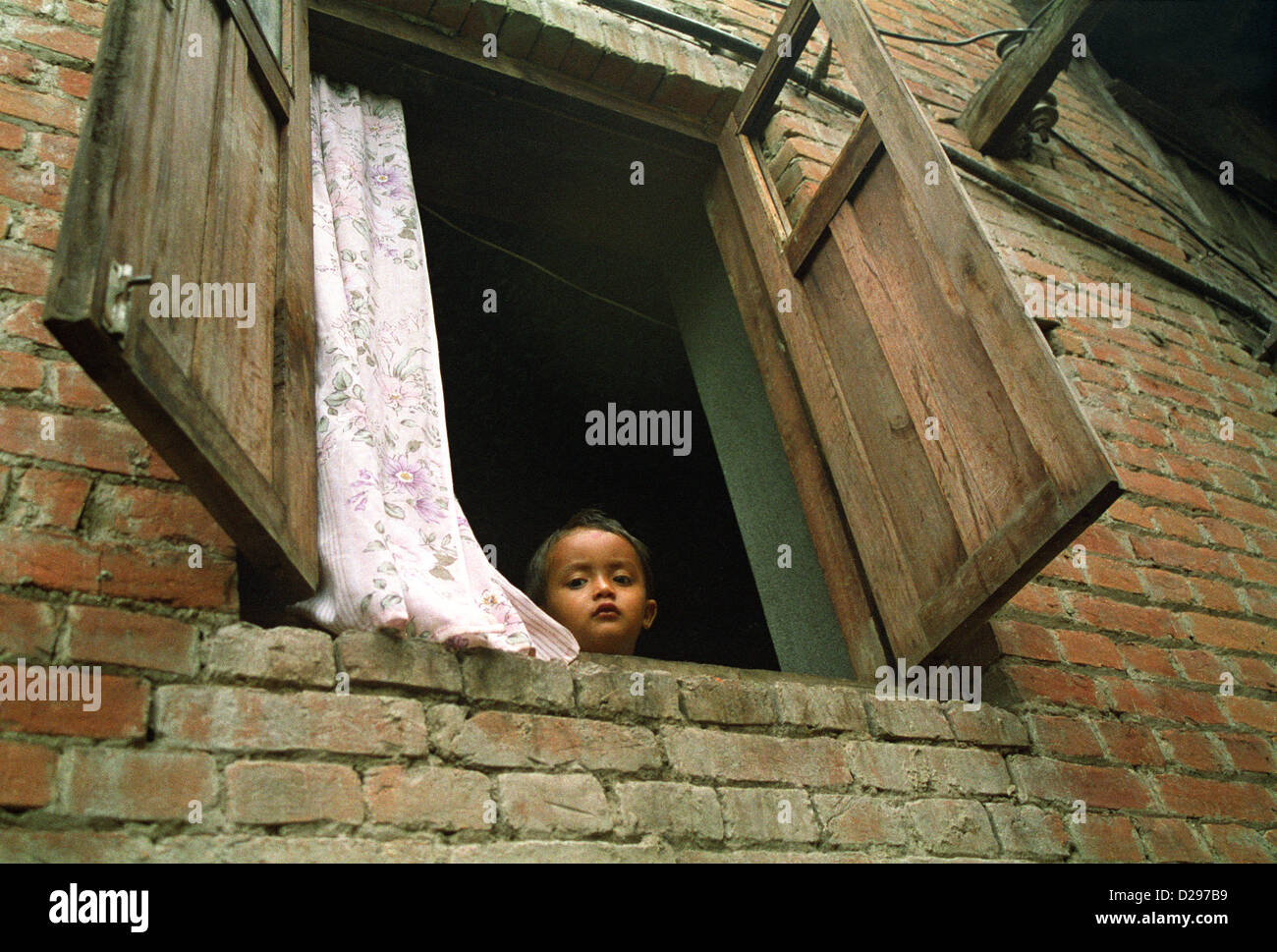 Nepal, Kathmandu. Girl Peeking Out Window.