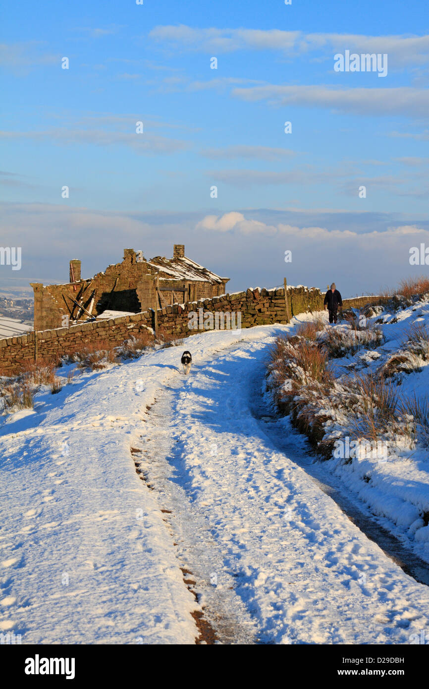 Walker with dog by derelict farm on the Bronte Way in winter snow ...