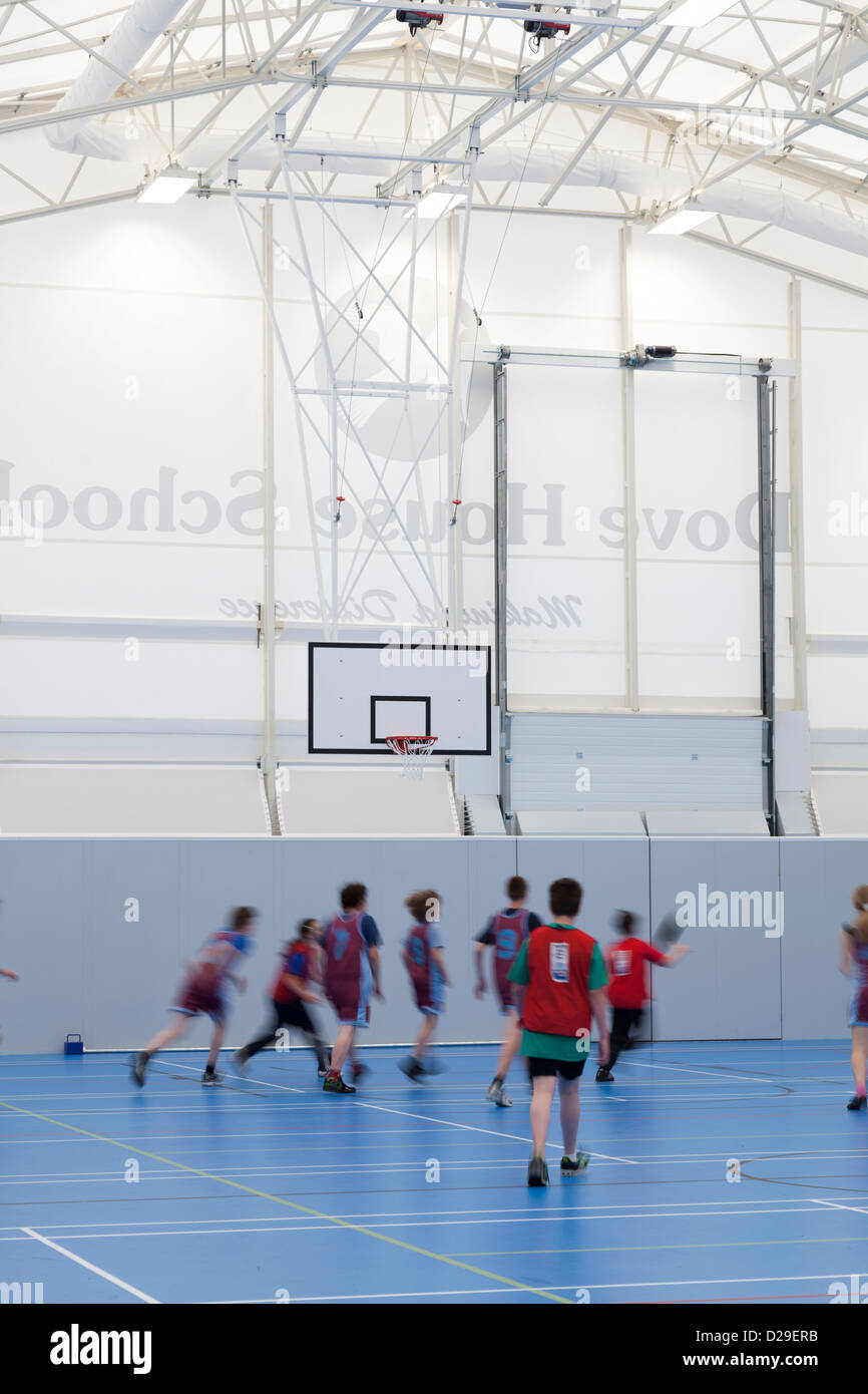 children palying basketball inside school sports hall Stock Photo