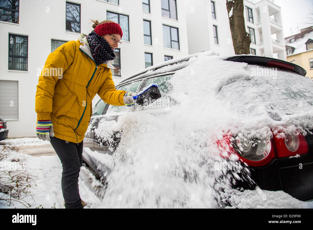Woman cleans her car from ice and snow. Stock Photo