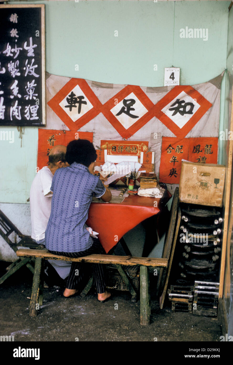Macao. Professional Letter Writer Discussing Letter With Client Stock Photo
