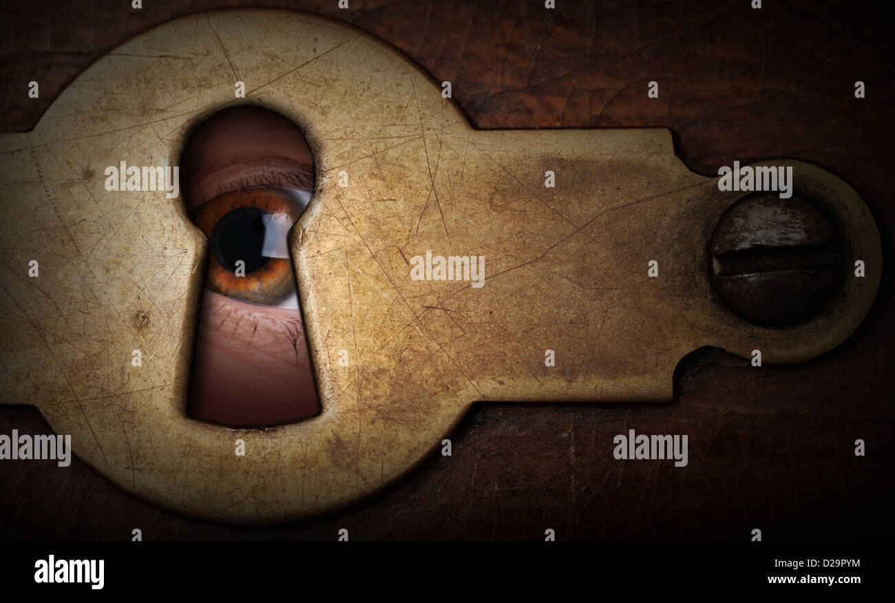 Brown eye looking through a vintage metal keyhole Stock Photo