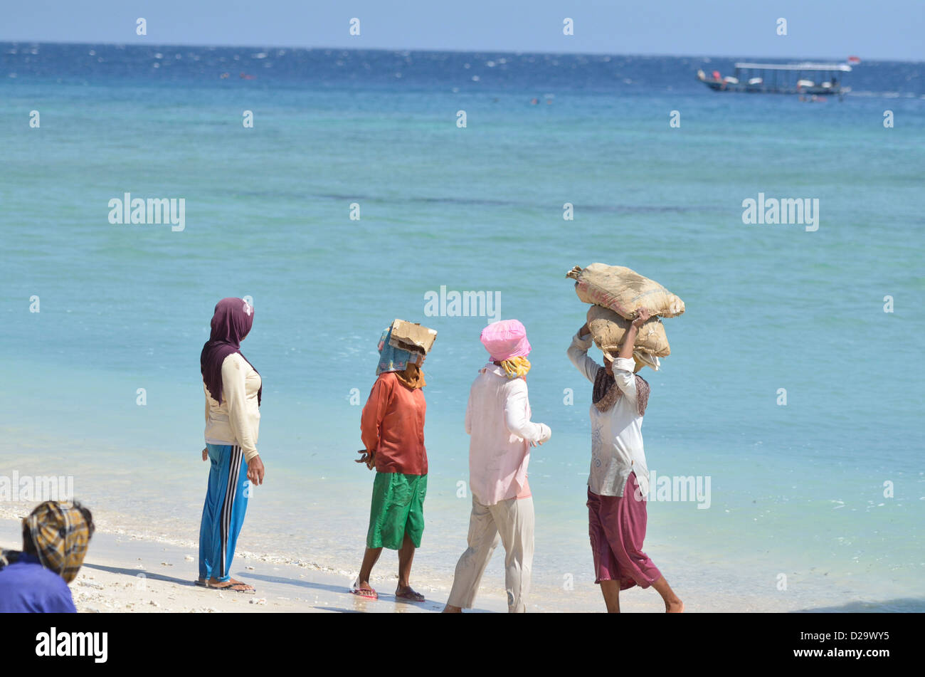 A group of indonesian women offload a full boat of concrete bags in the coral island at Gili Trawangan; Lombok, Indonesia. Stock Photo