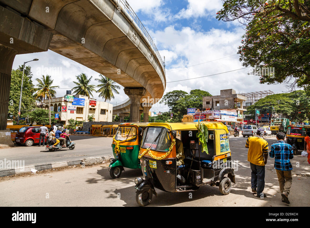 Auto rickshaws and traffic pass underneath the newly built Bangalore metro overpass, Bangalore, India Stock Photo