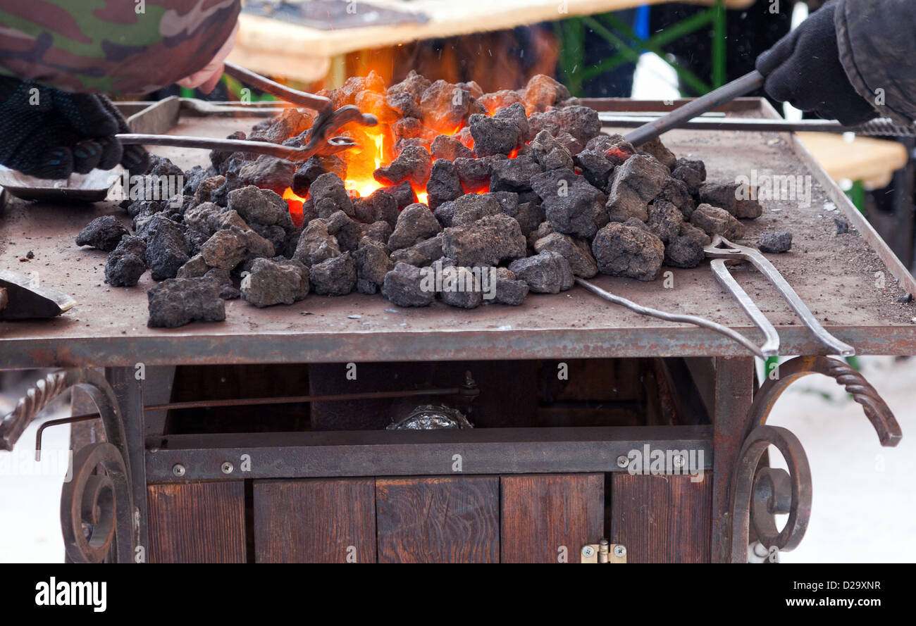 Craftsman blacksmith warming a piece of iron in the fire Stock Photo