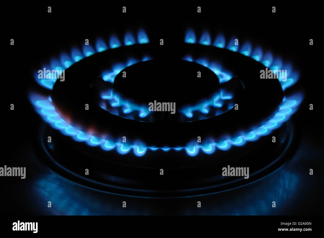 Gas cooker ring blue flames in darkness. Stock Photo