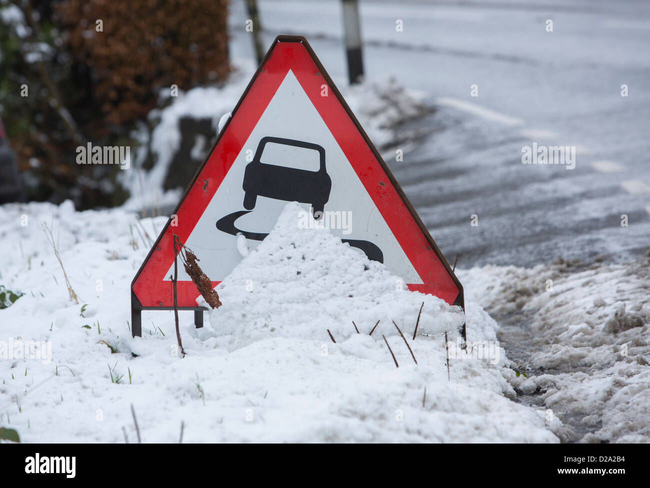 A slippery conditions ahead road sign partially covered by ...