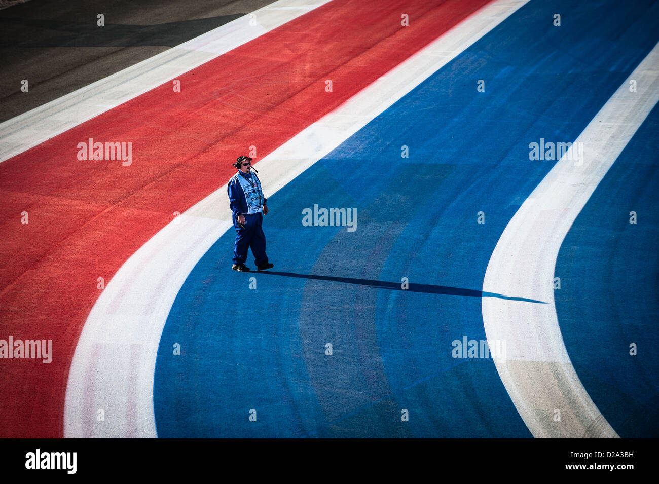 A track marshal walks across red, white and blue stripes beside the track at Circuit of the Americas, Austin, Texas Stock Photo