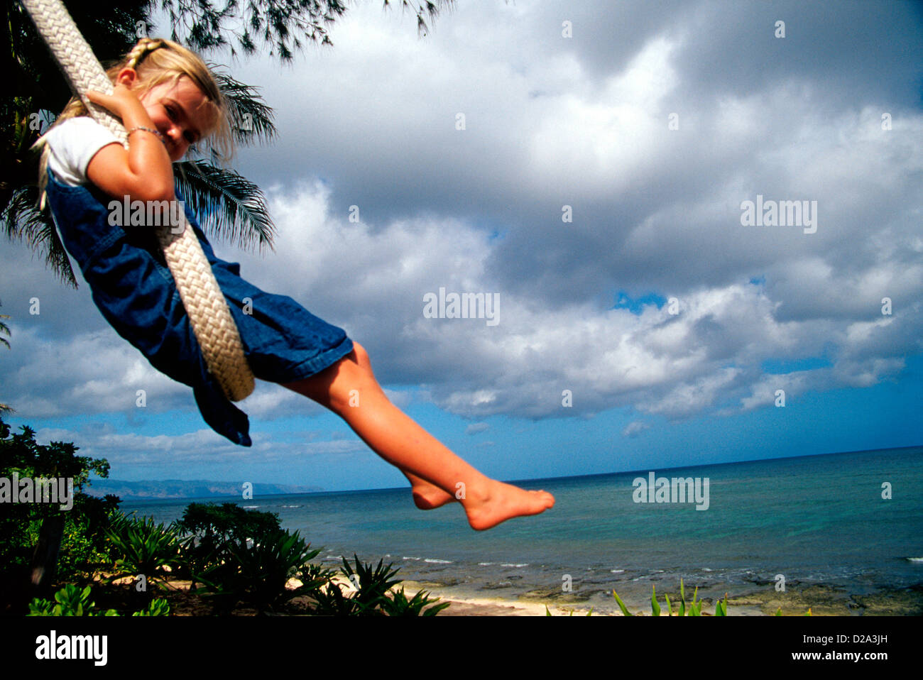 Girl (4) On A Rope Swing At Sunset Point On The North Shore Of Oahu