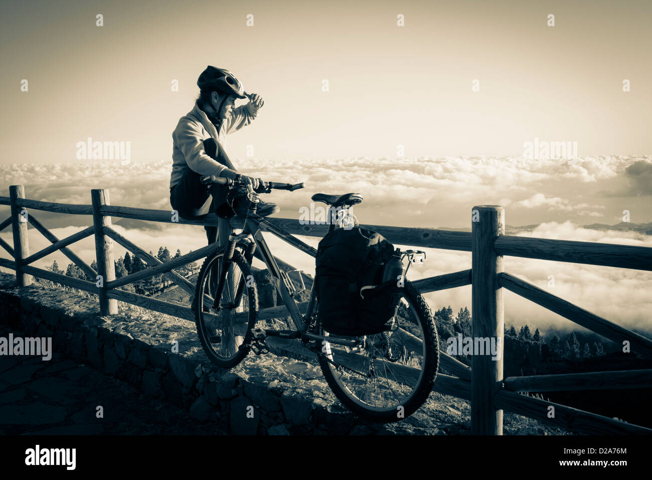 Woman with Mountain Bike above cloud layer at sunset at Pinos de Galdar on Gran Canaria, Canary Islands, Spain Stock Photo