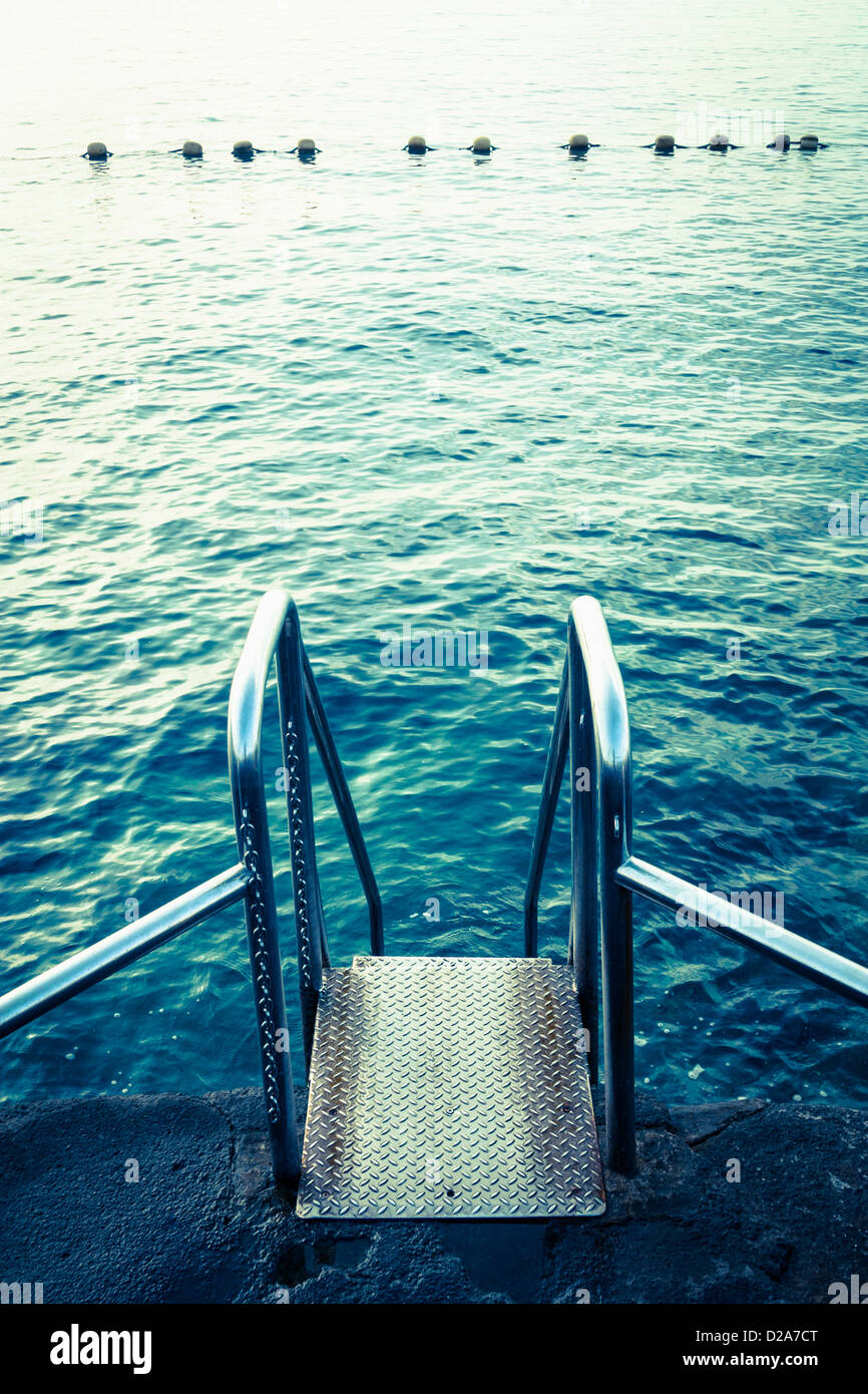 Steel steps leading to coastal swimming area on rocky coastline Stock Photo