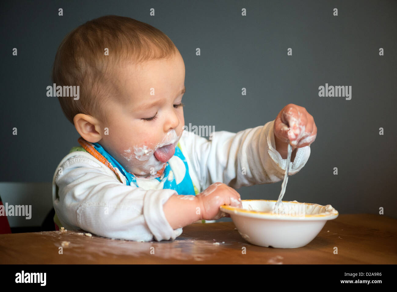 Berlin, Germany, a toddler with Schnute eats yogurt with a spoon Stock Photo