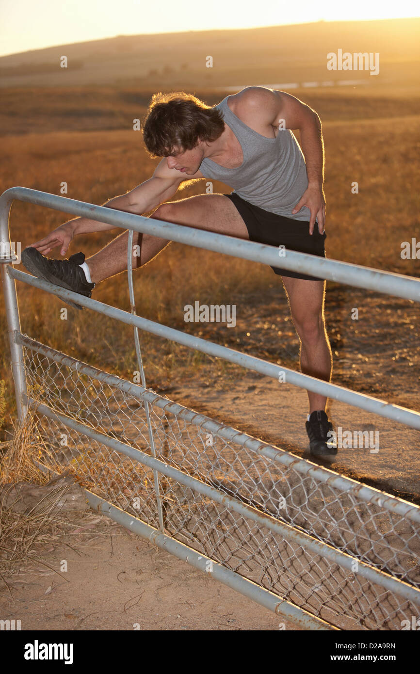 Man stretching on fence in rural field Stock Photo Alamy