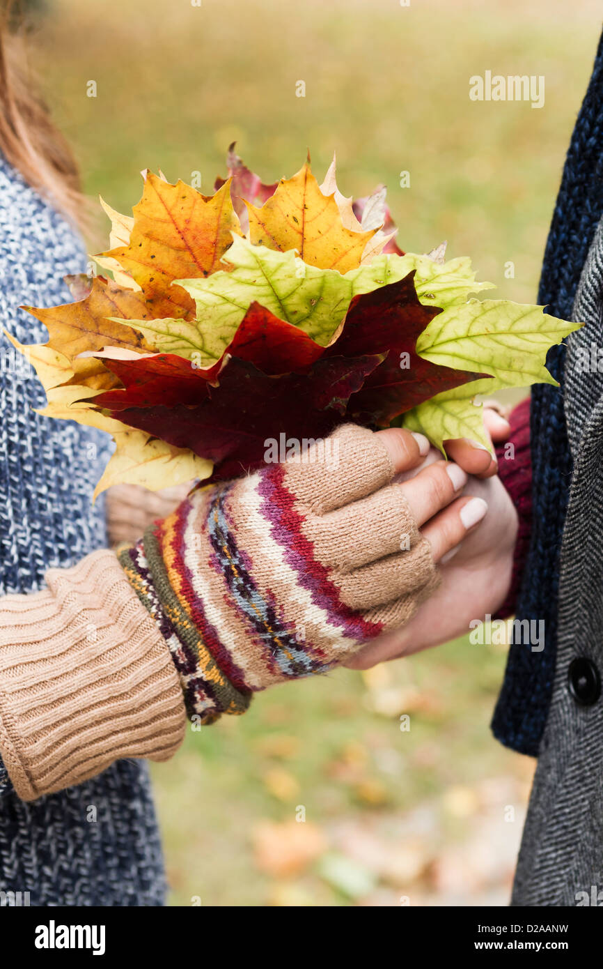 Close up of couple holding autumn leaves Stock Photo