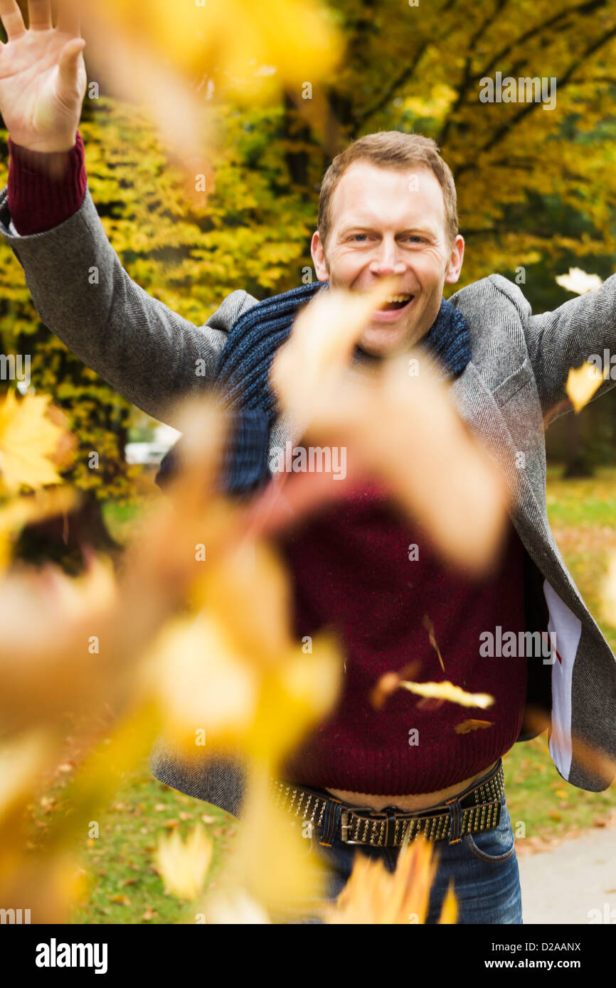 Man playing in autumn leaves Stock Photo