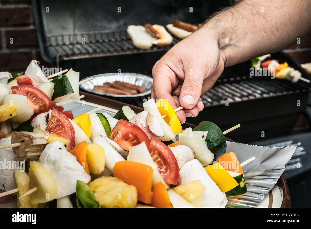 Man grilling vegetable skewers Stock Photo