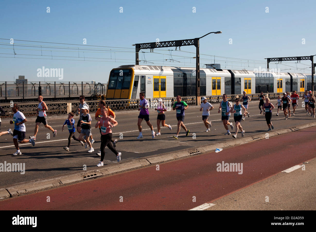 Fitness enthusiasts running across the Sydney Harbour Bridge with the suburban CityRail train in the background Stock Photo
