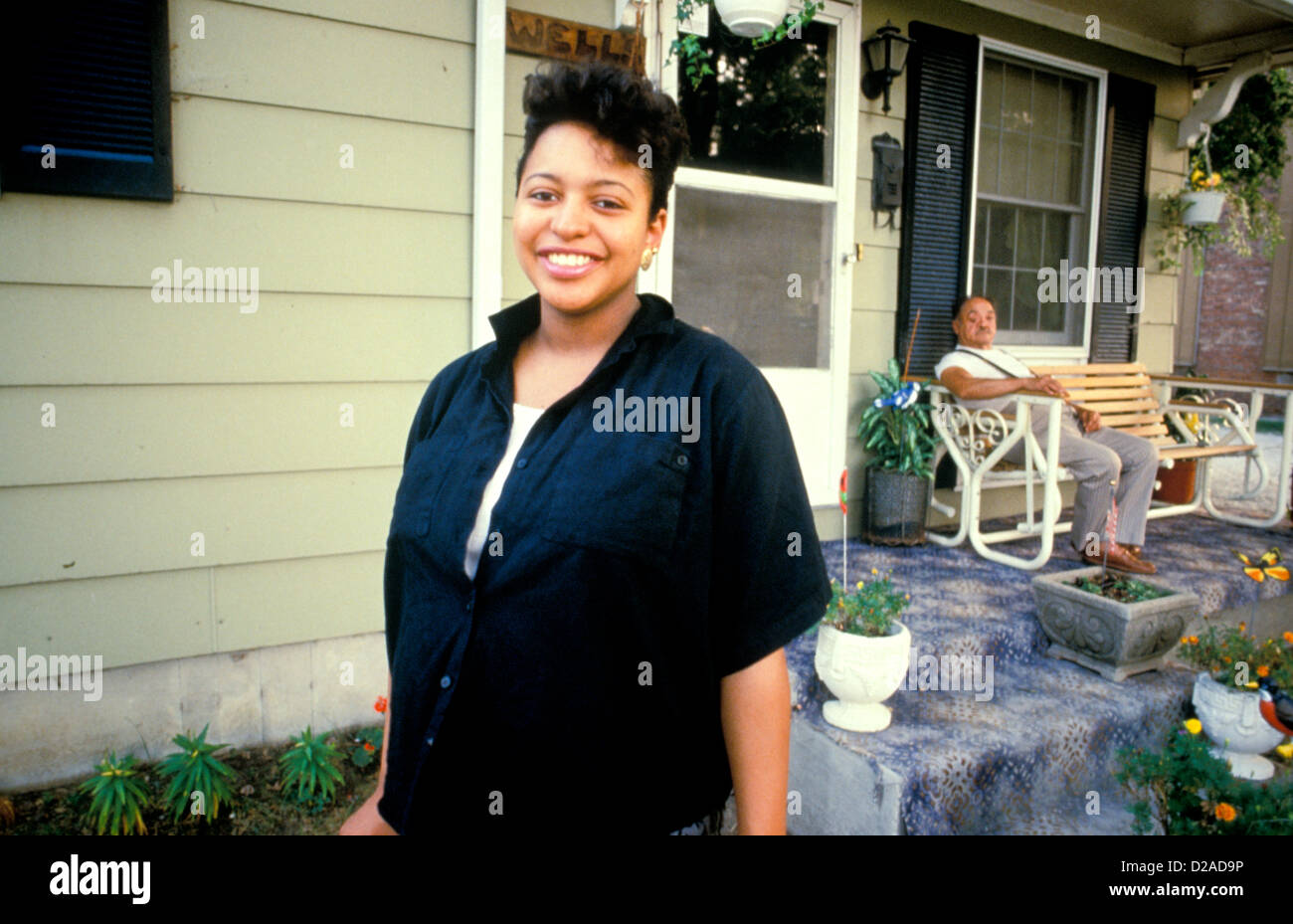 Woman Posing In Front Of Suburban Home. Stock Photo