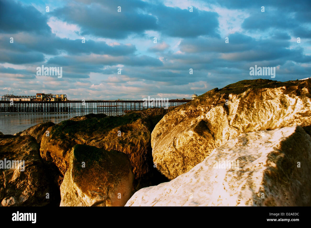 hastings seafront in january at sunrise showing the pier and beach rocks blue sky sea sand tide out Stock Photo