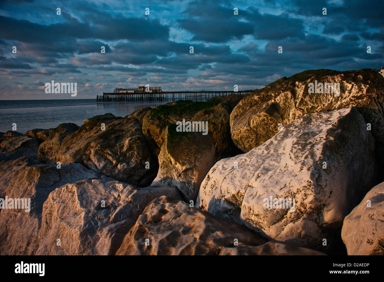 hastings seafront in january at sunrise showing the pier and beach rocks blue sky sea sand tide out Stock Photo