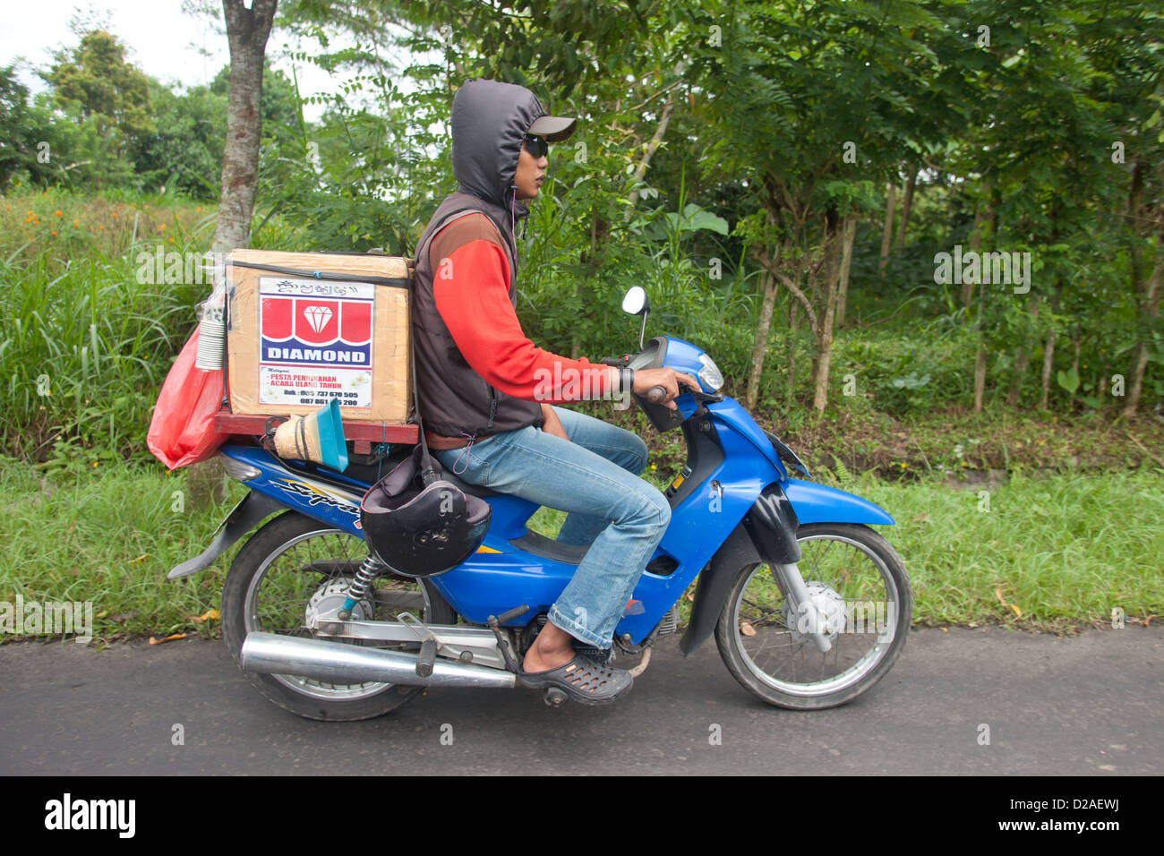 BALI - JANUARY 22. Balinese man carrying goods on bike in Bali on January 22, 2012 in Bali, Indonesia. Stock Photo