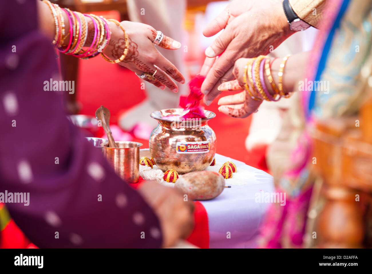 People throw flower petals into a vase during a Hindu wedding ceremony