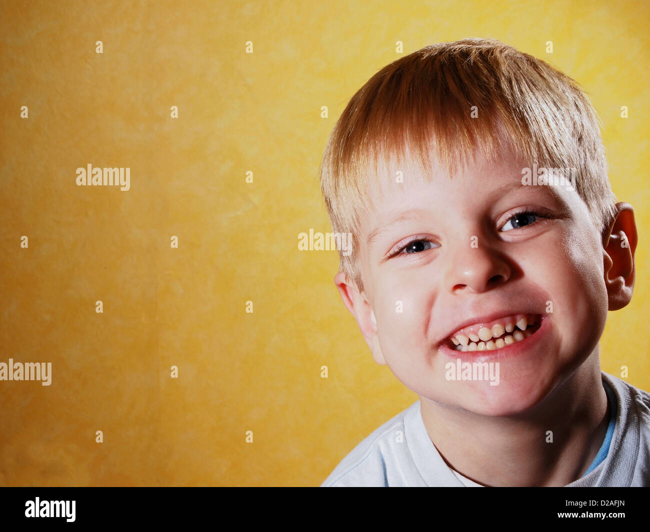 Portrait of happy joyful beautiful little boy isolated on yellow background Stock Photo