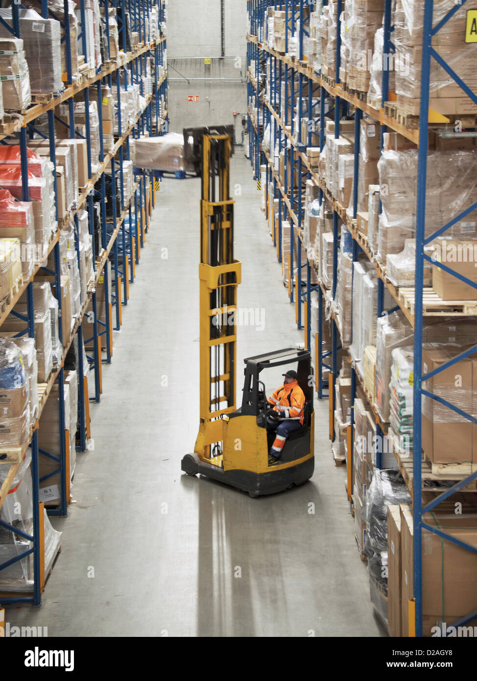 Worker operating forklift in warehouse Stock Photo