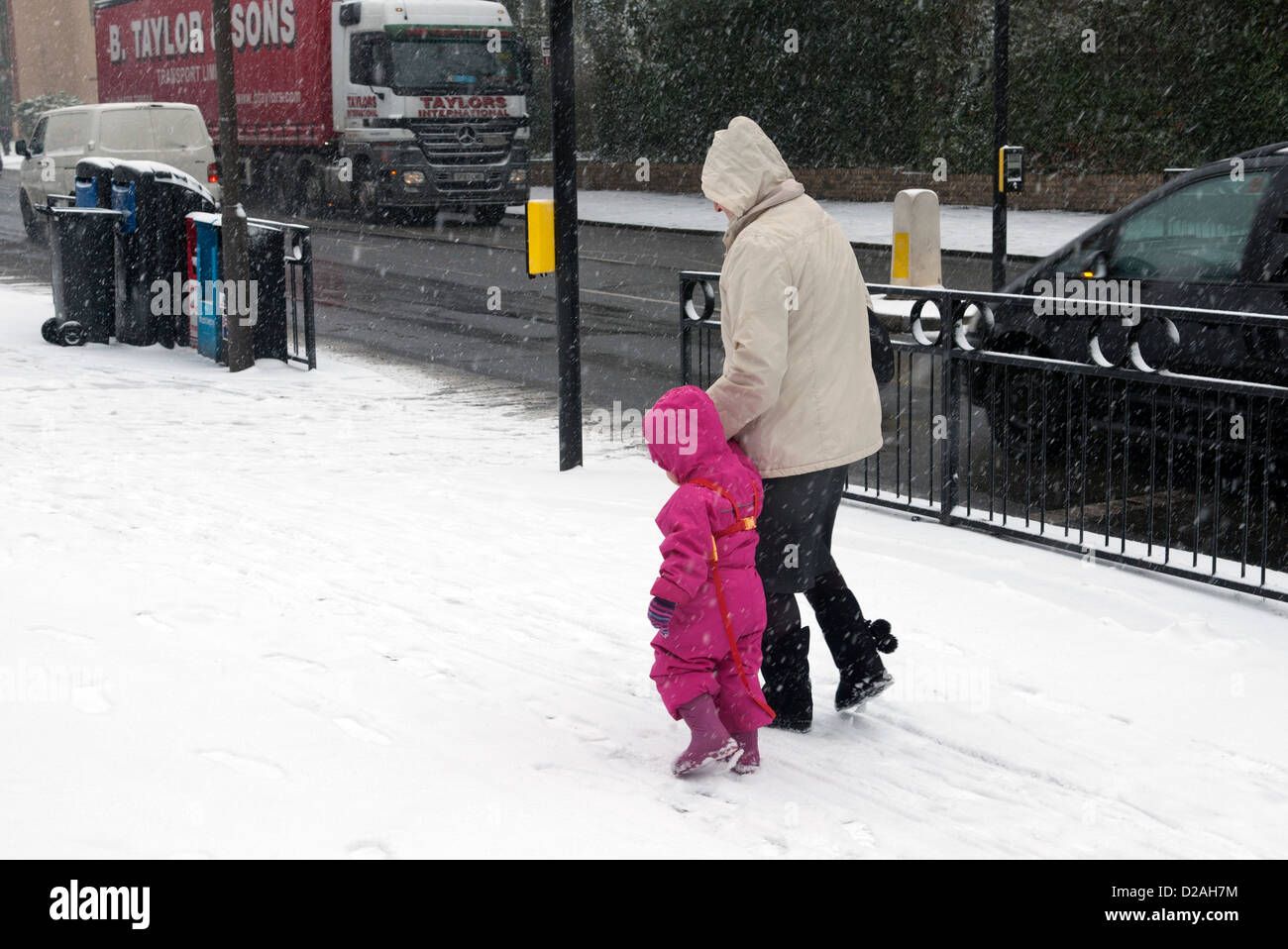 Woman helping a small child in a pink snow suit Stock Photo