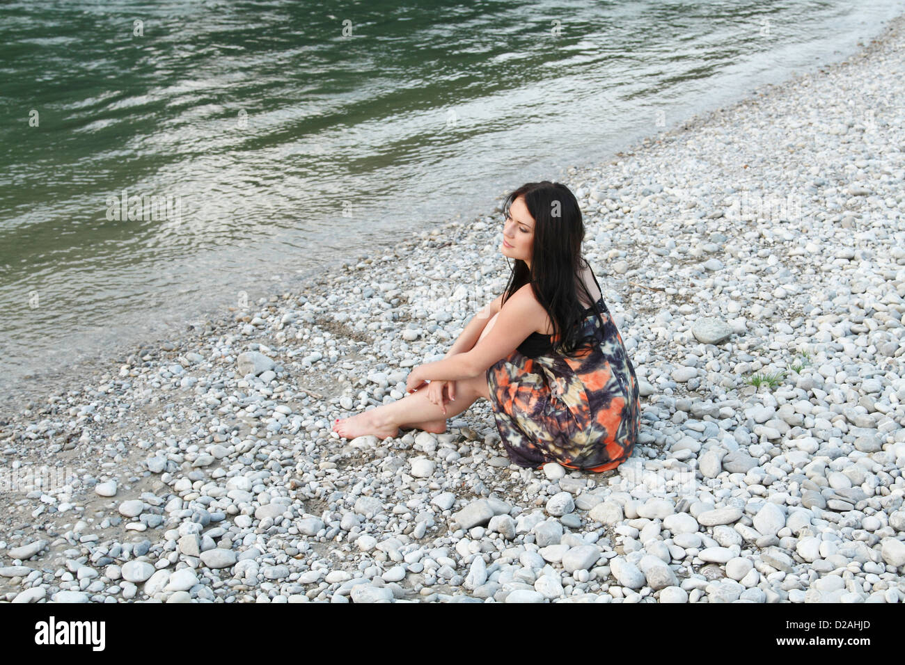 Woman sitting on rocky beach Stock Photo Alamy
