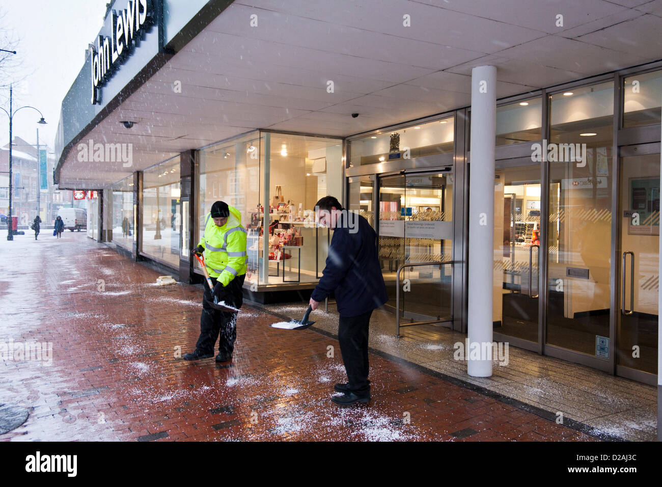 Two John Lewis employees grit the pavement outside the store in Reading