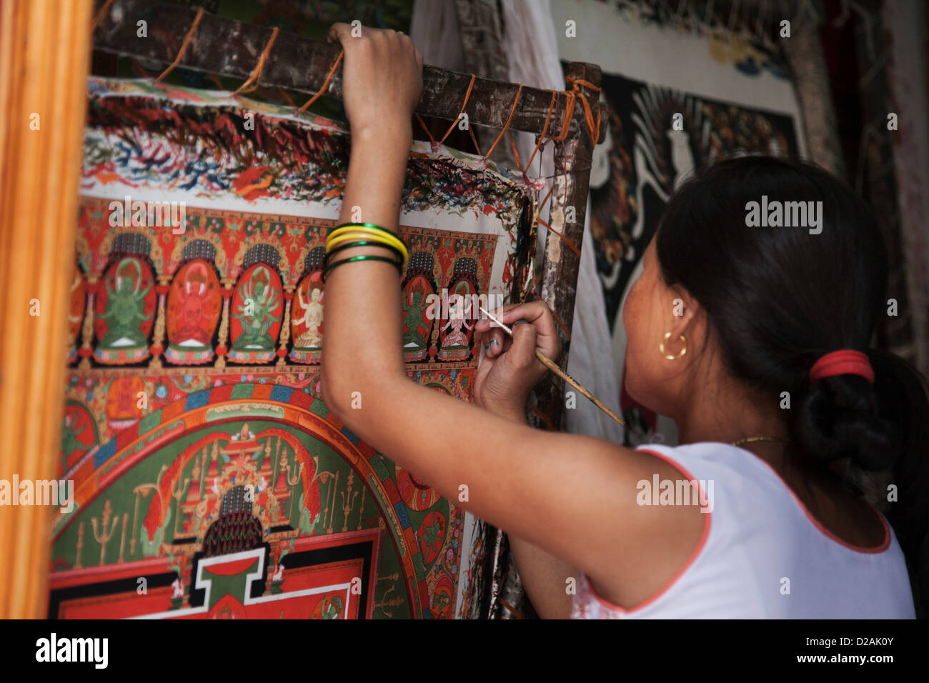A young Nepalese woman works on a painting in a gallery off the Bhaktapur Durbar Square. Stock Photo