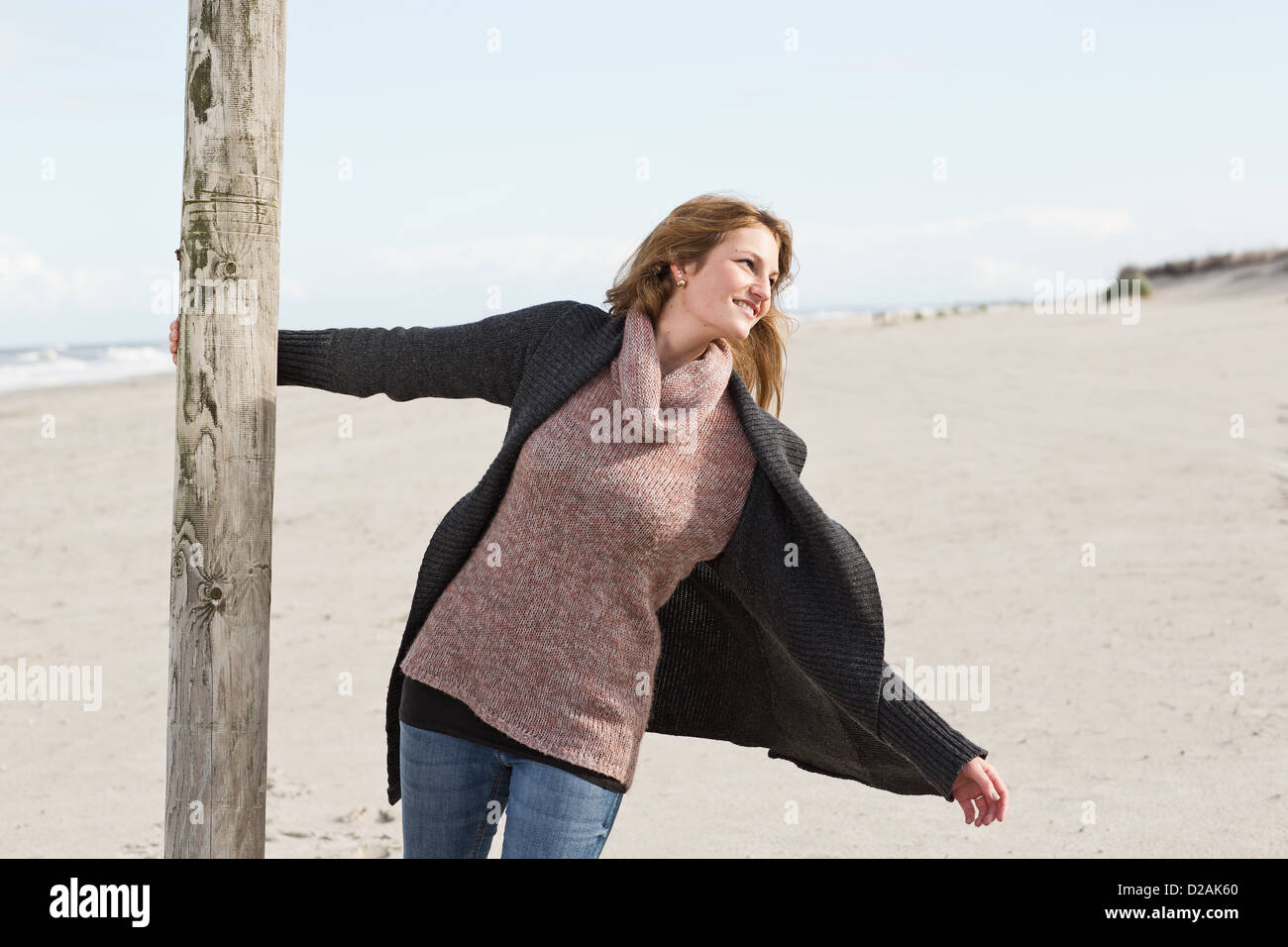 Woman swinging from pole on beach Stock Photo