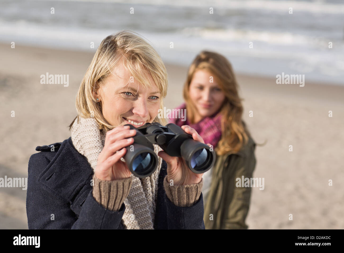 Woman using binoculars on beach Stock Photo