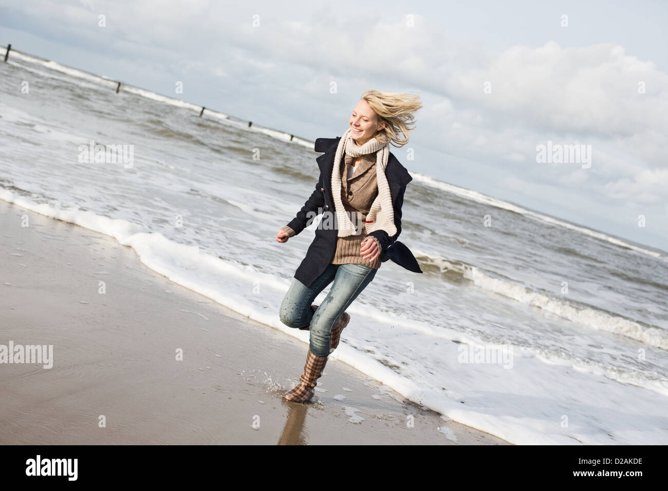 Smiling woman running on beach Stock Photo