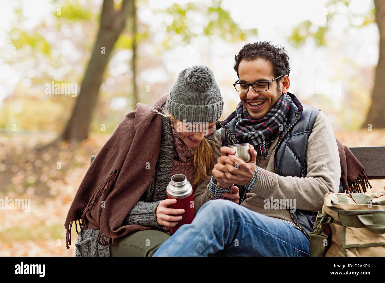 Couple drinking coffee on park bench Stock Photo