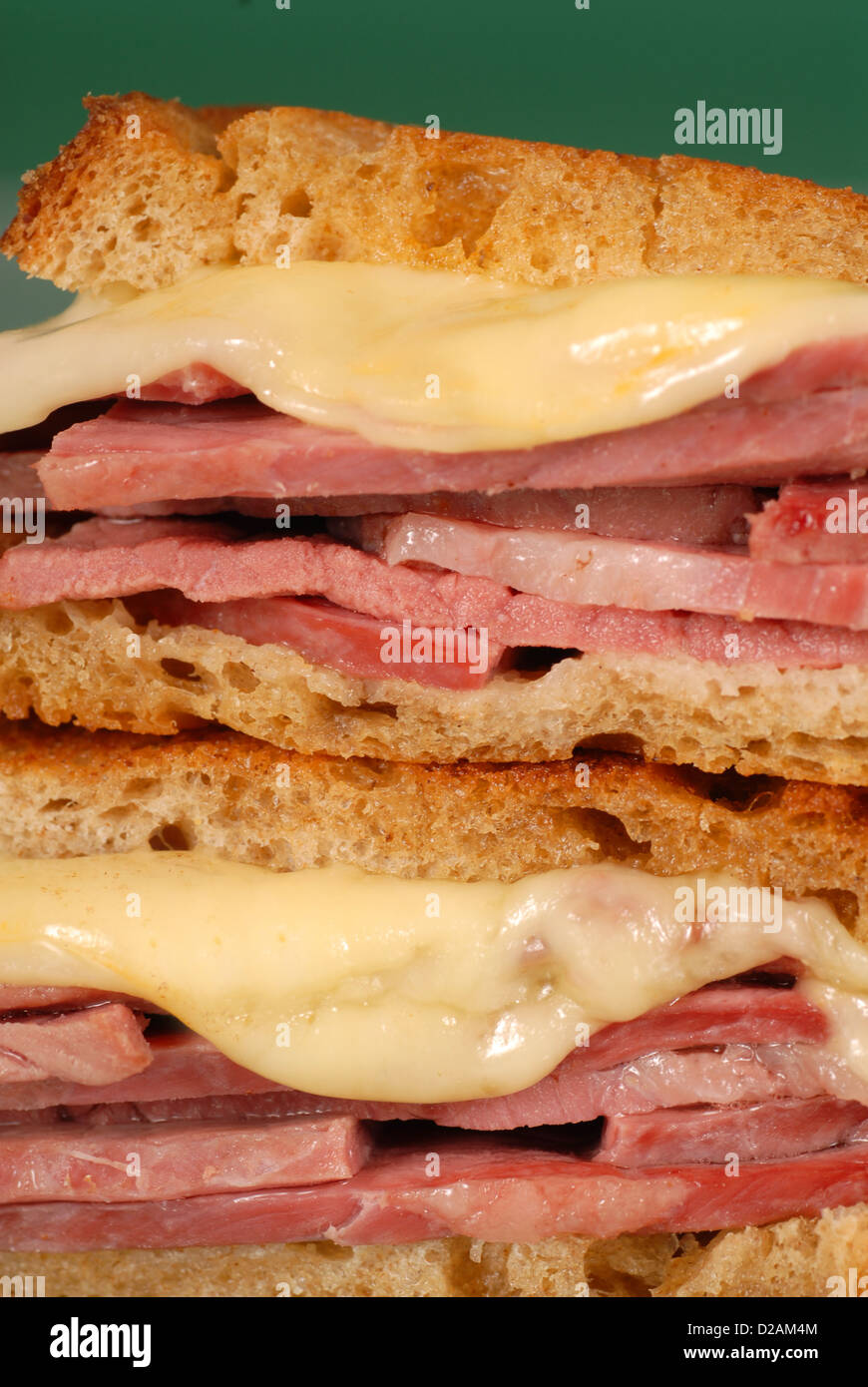 A closeup of a corned beef sandwich with melted swiss cheese on rye