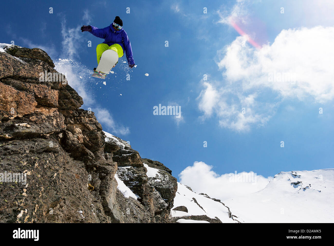 Snowboarder jumping on rocky slope Stock Photo