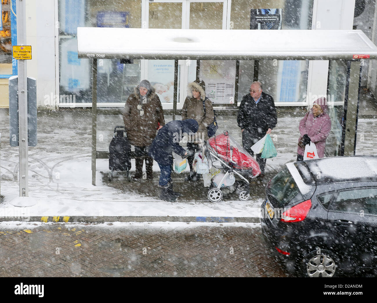 Commuters waiting at a bus stop in the snow in Worcester Park, Sutton, Surrey, England, UK. 18/01/2012 Stock Photo