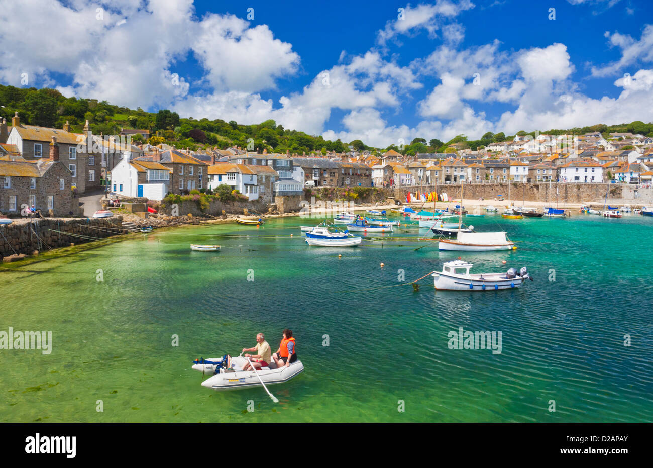 Family rowing in a small boat in amongst the Small fishing boats in Mousehole harbour Cornwall England GB UK EU Europe Stock Photo