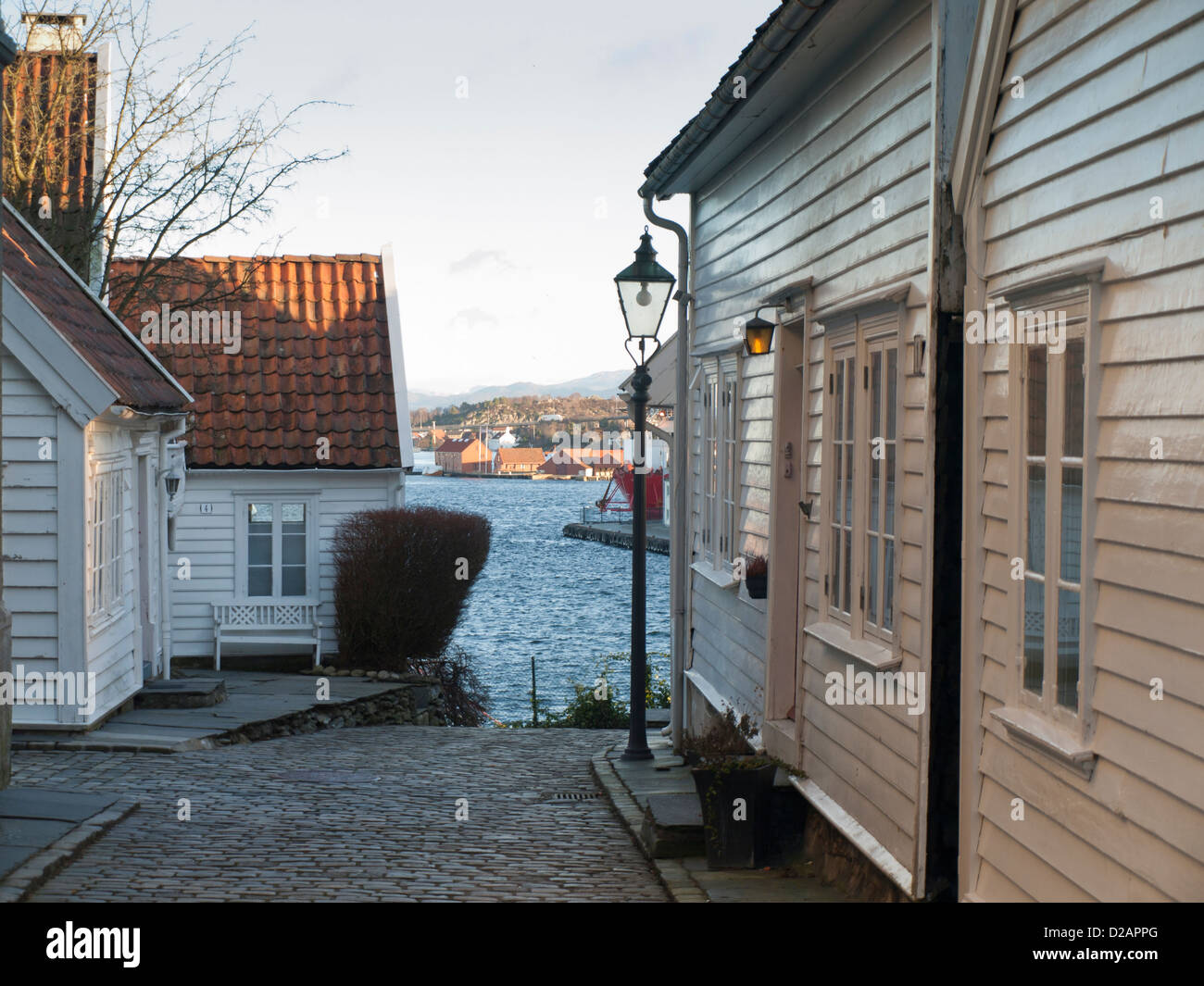 Steep cobbled street and wooden houses in Old Stavanger  Norway  a tourist attraction and recidential area. Harbour and fjord can be seen below Stock Photo