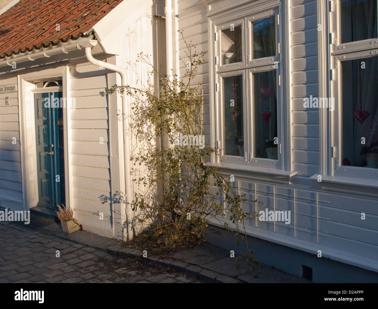 Detail of cobbled street in Old Stavanger Norway. Quaint old white wooden paneled houses from sailship era Stock Photo