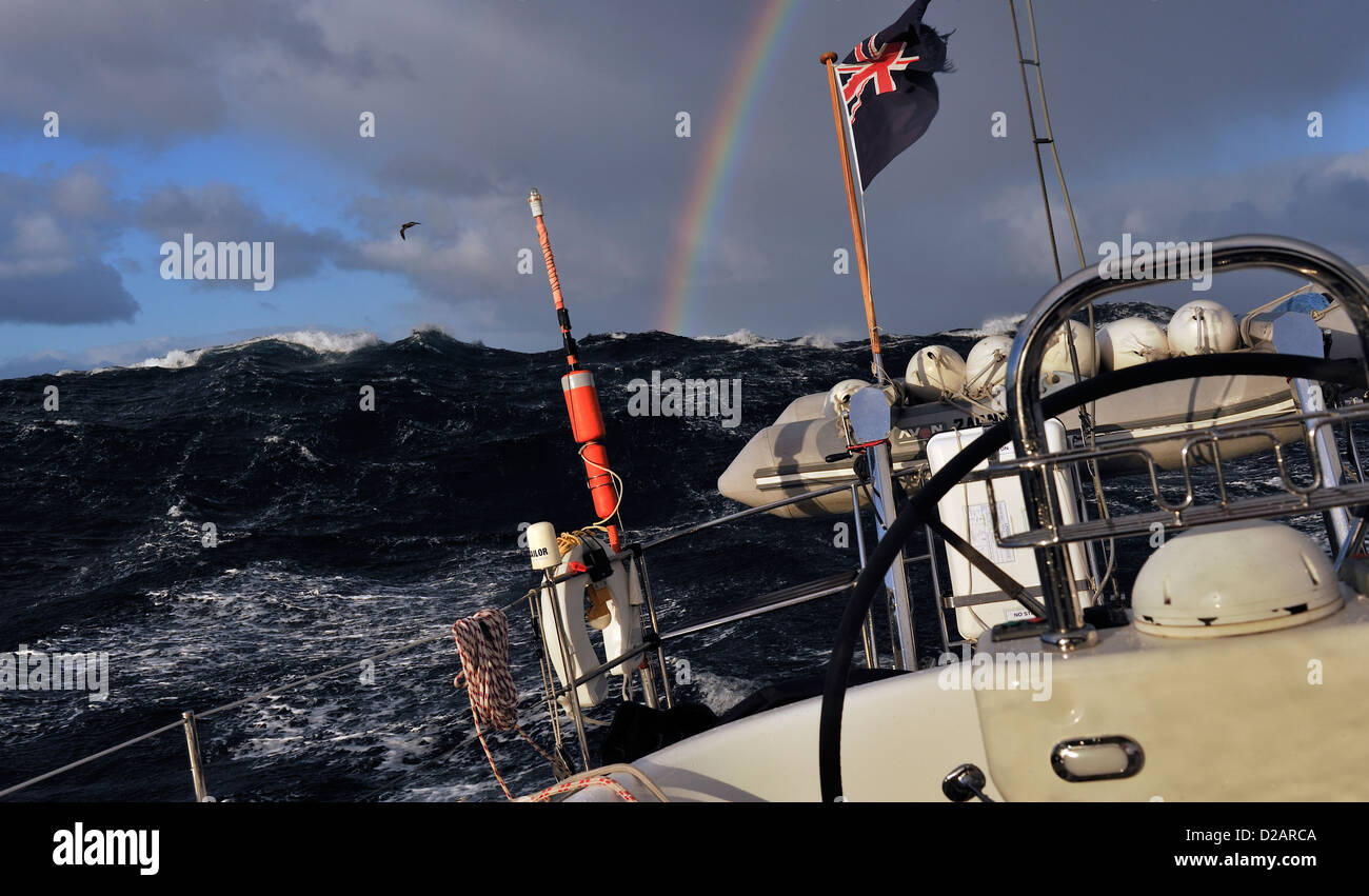 Rainbow and large following seas seen looking astern from a yacht, an Oyster 46, sailing offshore on passage across the Tasman Sea from Tasmania to NZ Stock Photo