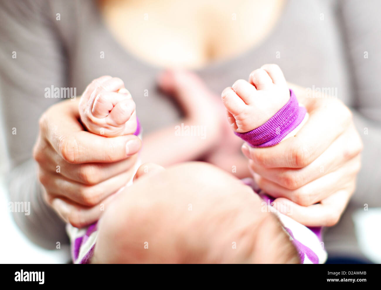 Overhead cropped view of a mother holding a tiny baby's hands in her own with focus to the hands Stock Photo