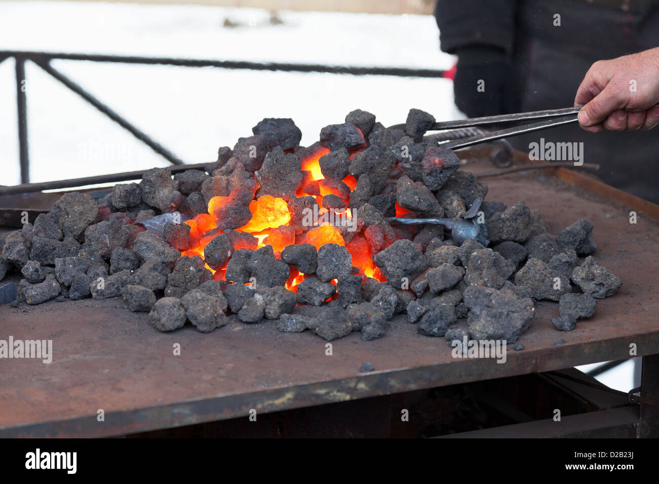 Craftsman blacksmith warming a piece of iron in the fire Stock Photo